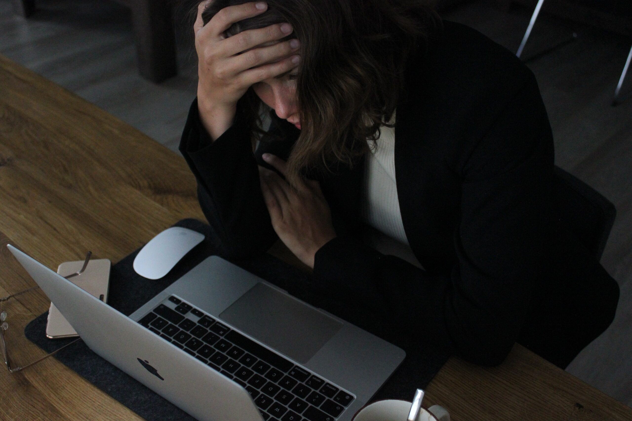 Stressed woman staring at her computer with a hand on her head