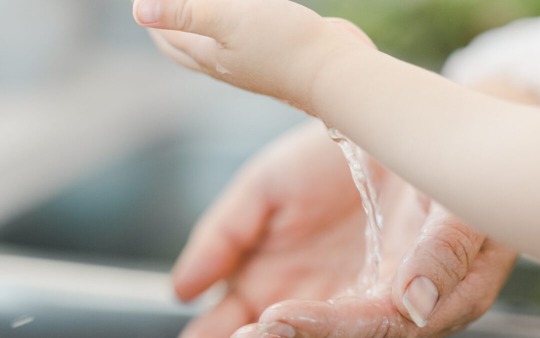 Mother and daughter washing their hands with warm water