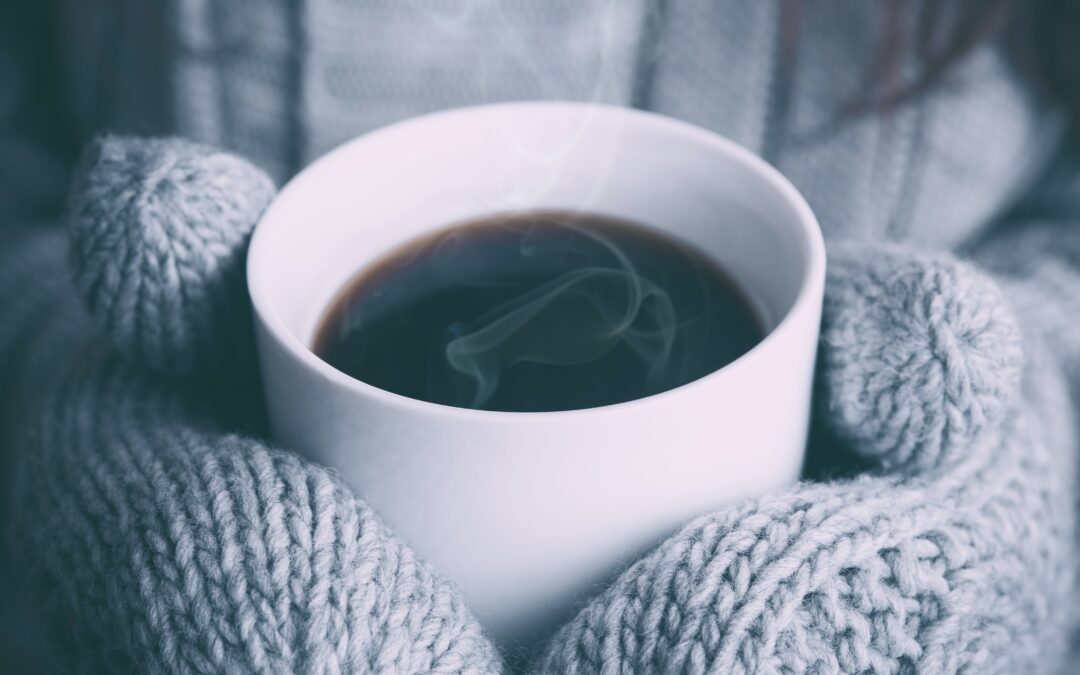 Gloved hands holding a cup of coffee