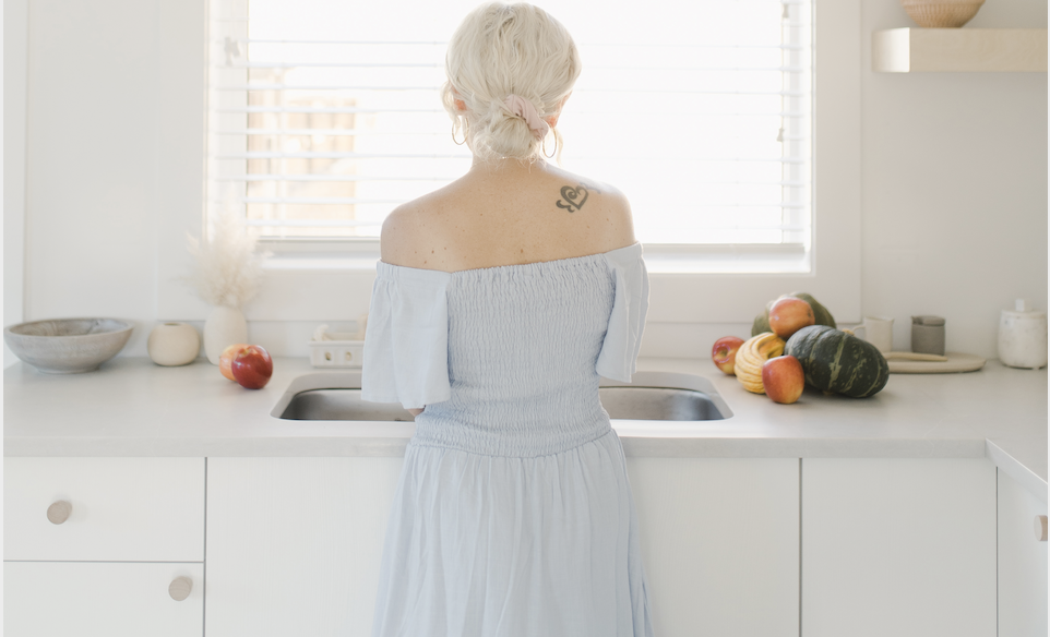 Meagan from behind standing at the sink contemplating